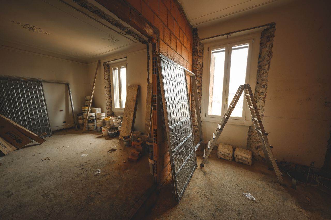 Accueil Interior view of a room under renovation with construction materials and a ladder.