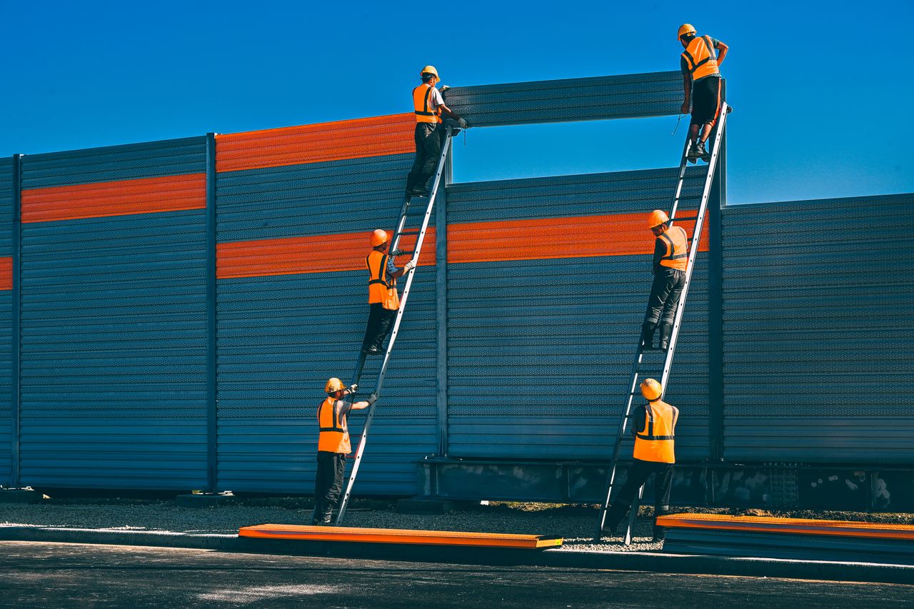 Accueil Workers in safety gear install a noise barrier on a highway in Moscow.